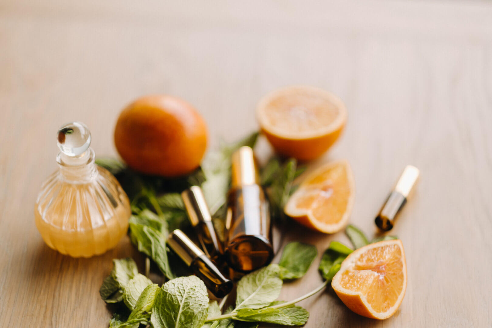 Essential oil in bottles with the aroma of orange and mint lying on a wooden surface