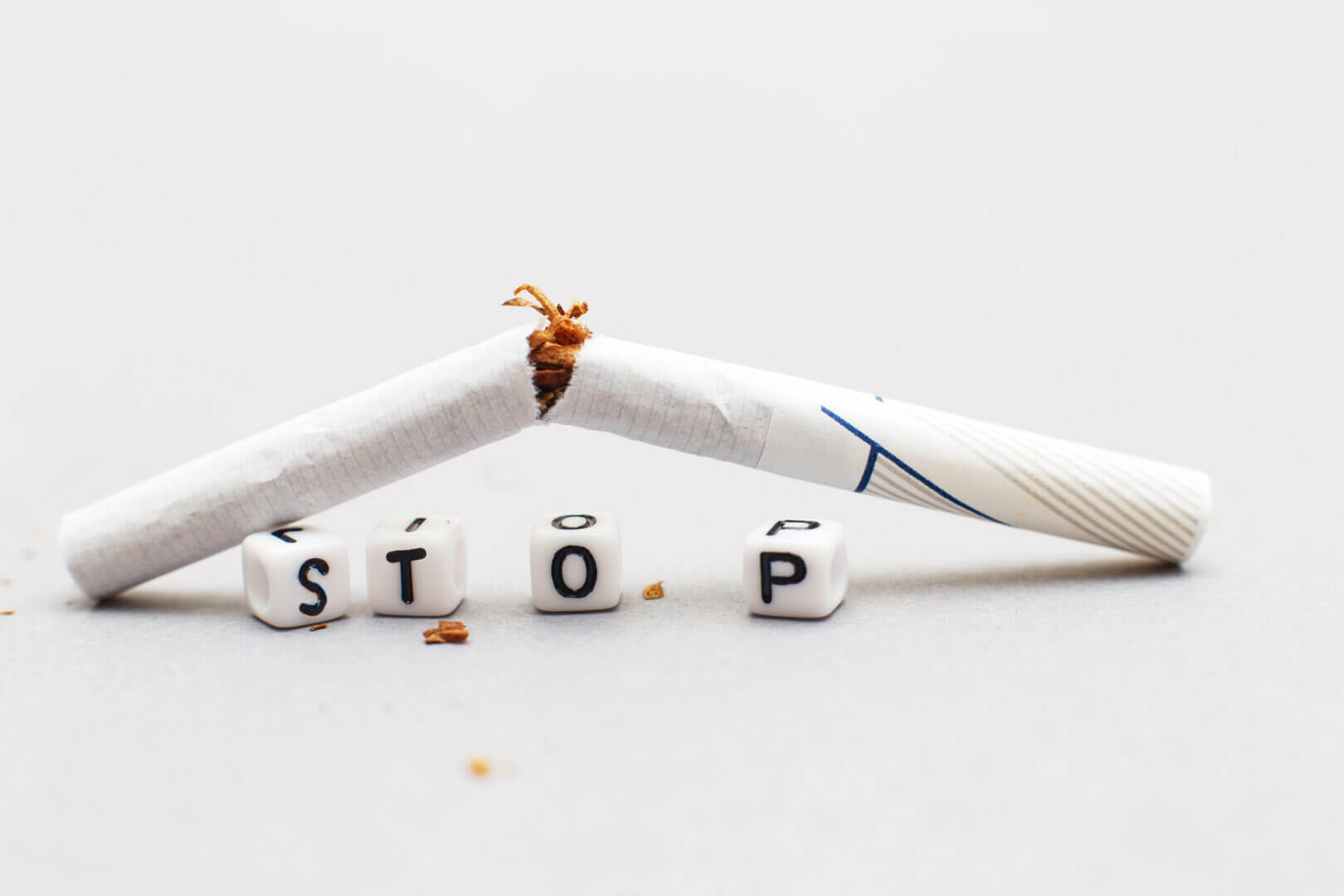 broken cigarette with the word stop on gray background close. stop smoking concept